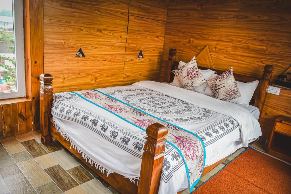 1 dormitorio con 1 cama con pared de madera en Hotel Riverside with Swimming pool, en Sauraha