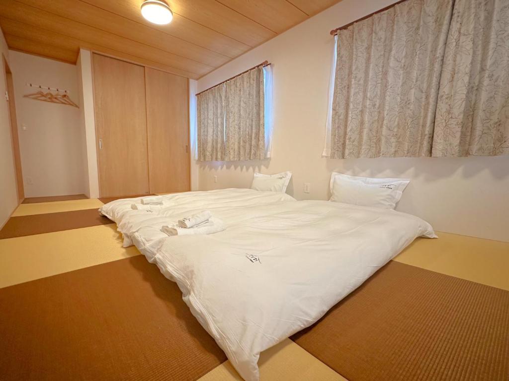 1 cama blanca grande en una habitación con ventana en ヴィラ山間堂Premier Garden Villa BBQ Bonfire Fuji view Annovillas Sankando, en Fujikawaguchiko