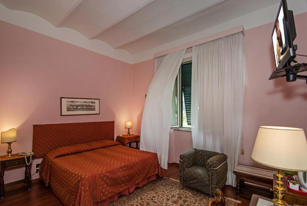 a bedroom with a bed and a chair and a window at Hotel Rex in Lucca