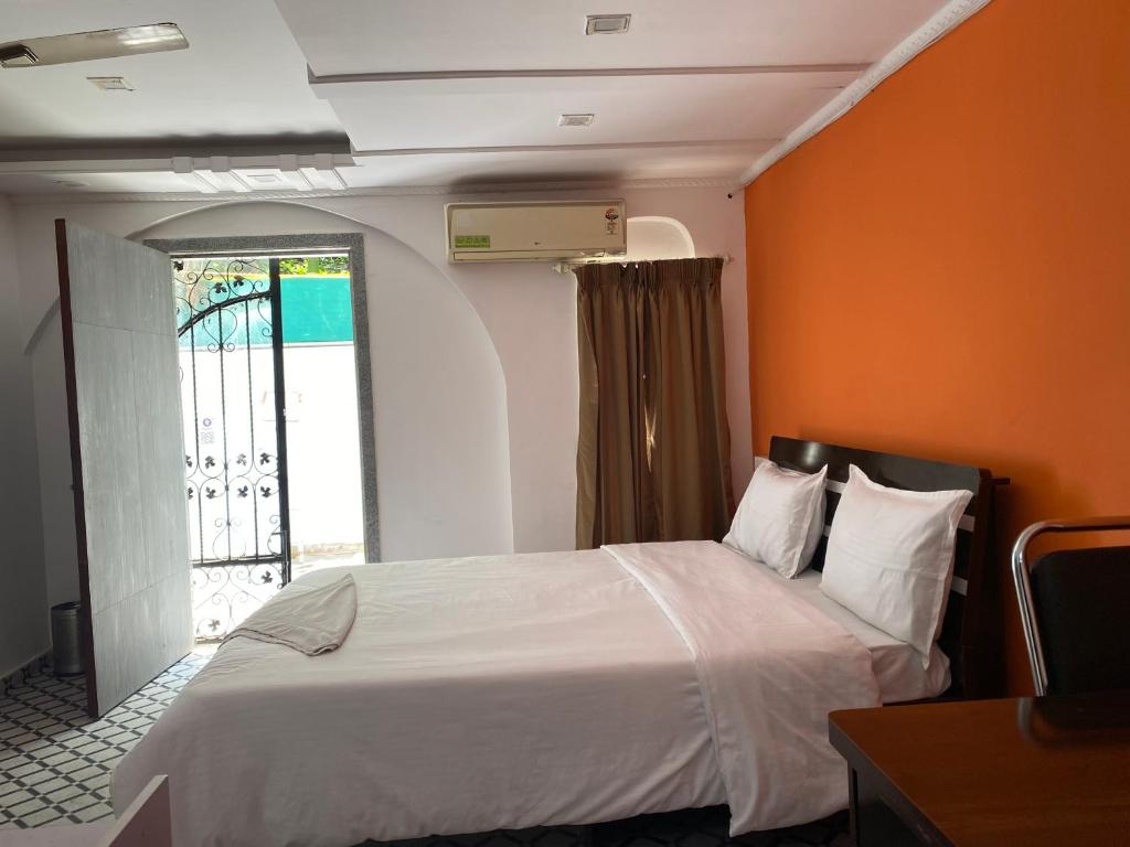 ein Schlafzimmer mit einem Bett mit einer orangefarbenen Wand in der Unterkunft Relaxing 3 Ac Room Near Pune Airport Kalyani Nagar in Pune