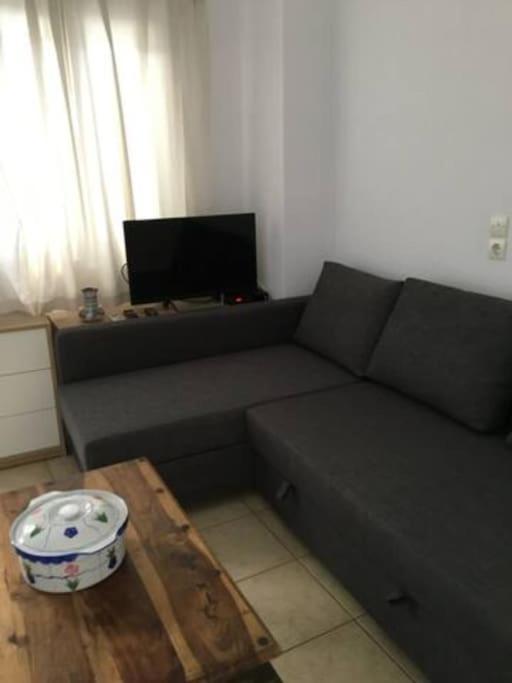 a living room with a gray couch and a table at Marditsa's House by the sea in Serifos Chora