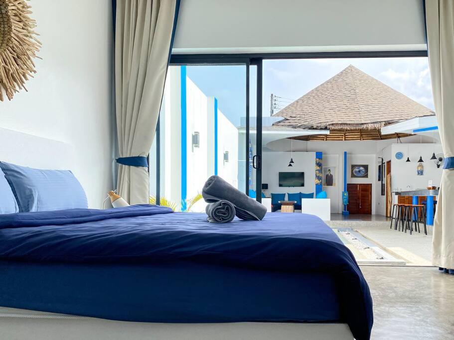 a bedroom with a blue bed with a view of a patio at Magritte - Balinese Style Cosy Villa in Amphoe Koksamui