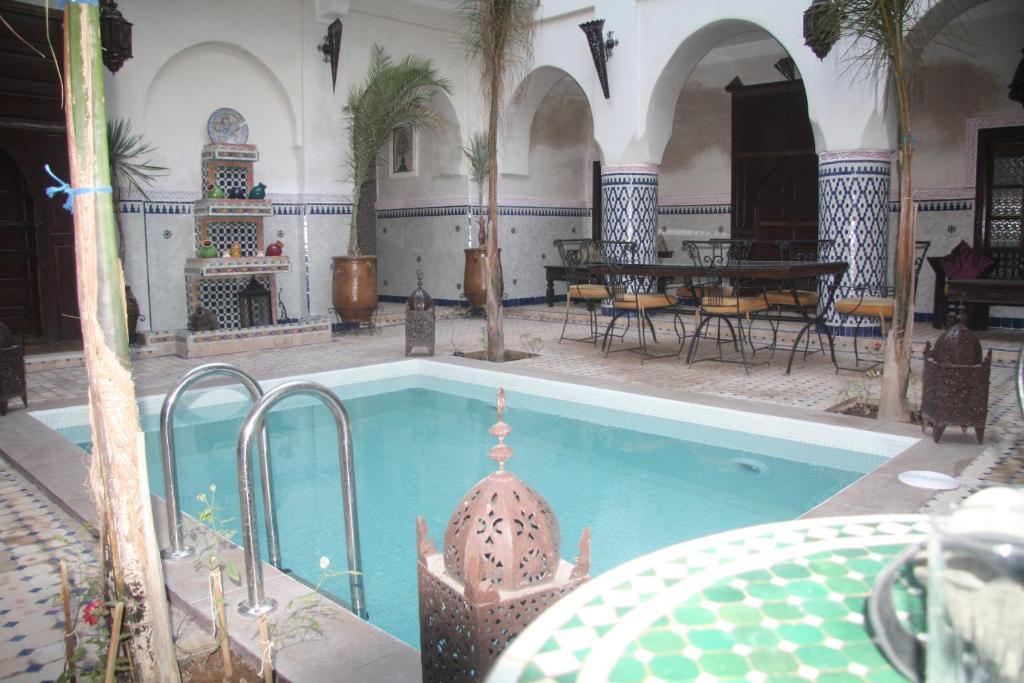 a swimming pool in a building with a table and chairs at Riad Dar Moulay Ali in Marrakesh