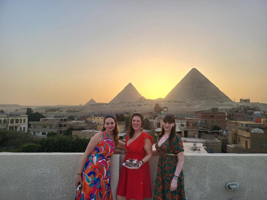 three women standing on a ledge in front of the pyramids at AliBaba Pyramids View Inn in Cairo