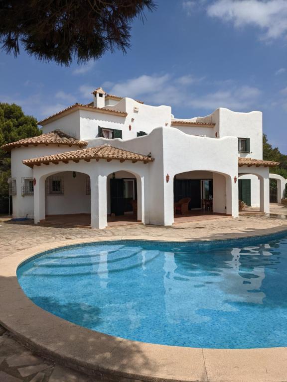 una casa con piscina frente a ella en Villa Vivaldi 100m sea & panoramic sea view, en Cala Pi