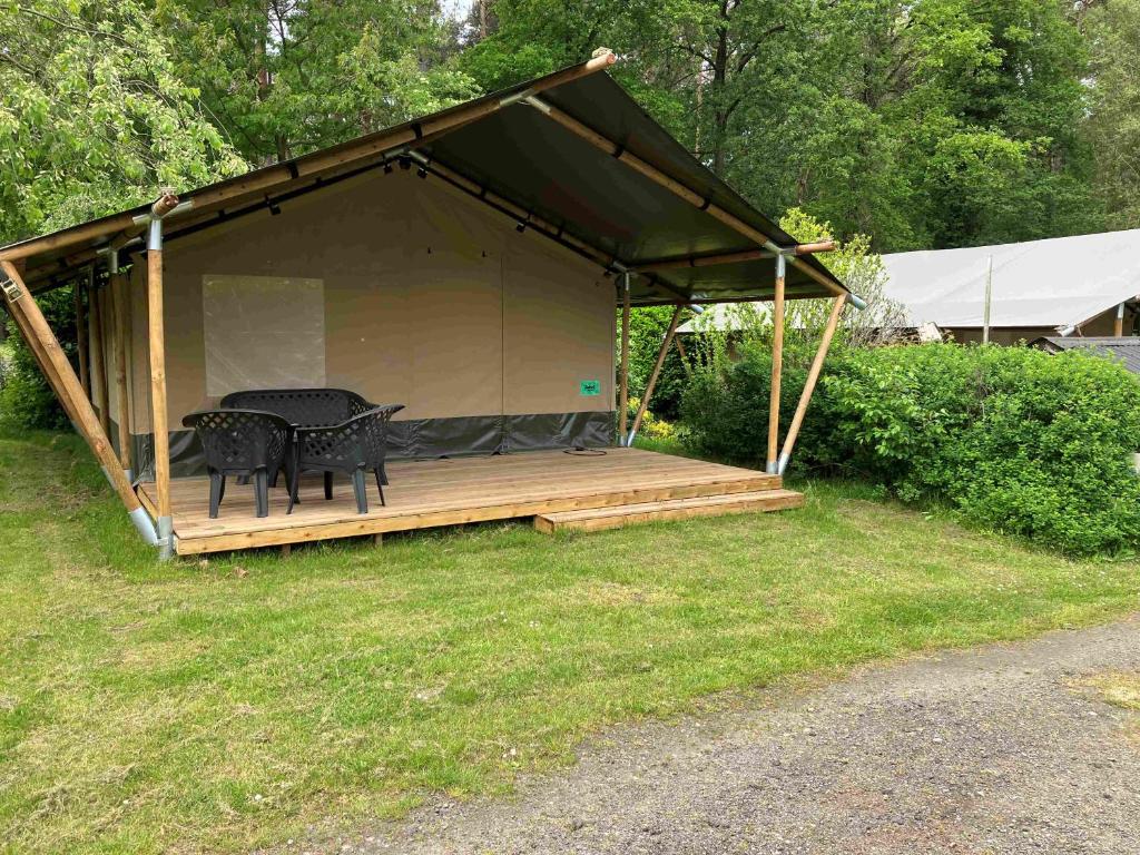 a tent with a table and chairs on a deck at Safaritent voor 4 personen in Zwiggelte