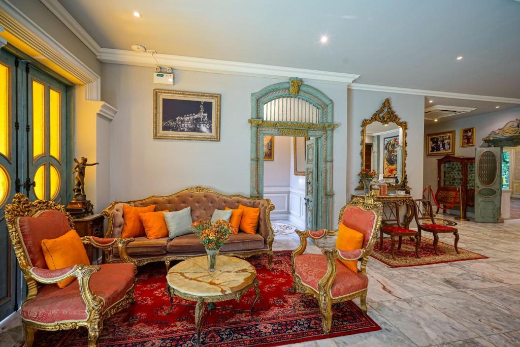 An ornate sitting room offers a tufted sofa, carved armchairs, marble flooring, and traditional décor.