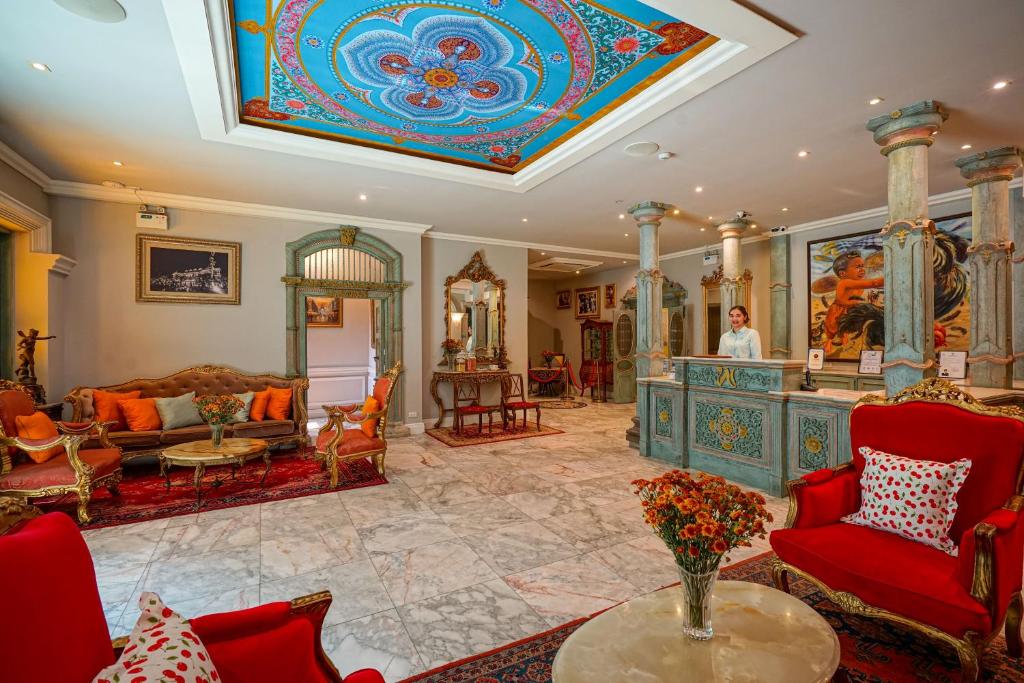 A richly decorated reception lounge combines red seating, marble floors, and a painted ceiling.