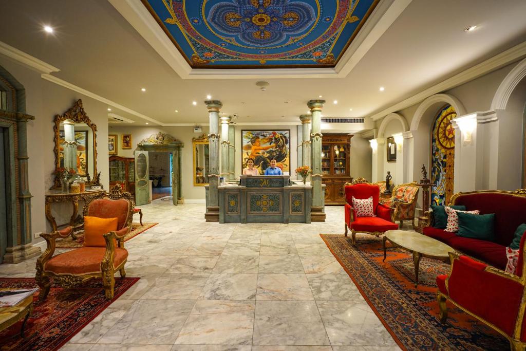 An ornate lobby lounge surrounds a decorated reception desk beneath a painted ceiling.