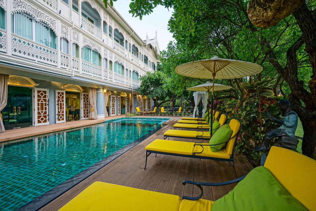 uma piscina com espreguiçadeiras amarelas e um guarda-sol em At Pingnakorn Riverside em Chiang Mai