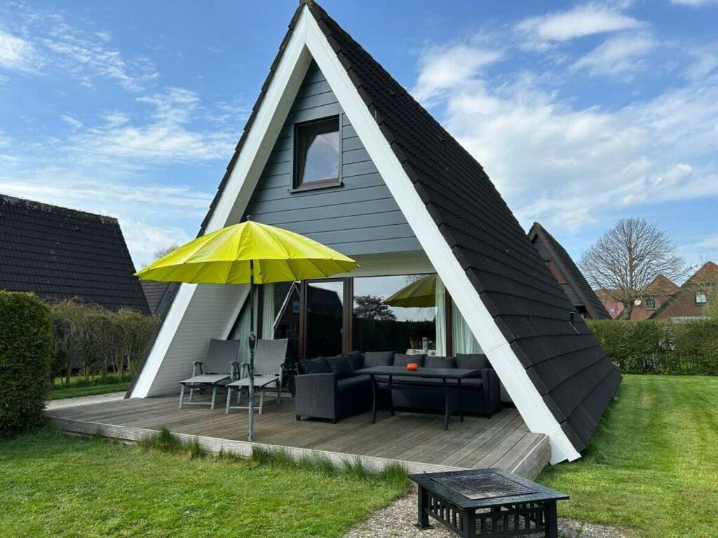 a triangular roofed house with a table and a yellow umbrella at Flower in Carolinensiel in Carolinensiel