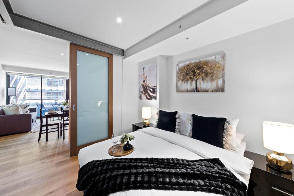 a bedroom with a large bed and a living room at Amazing & Cozy Apt Right Next to Southern Cross in Melbourne