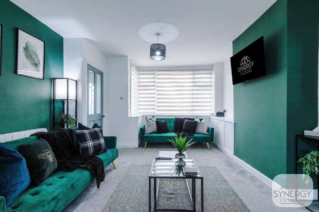 a living room with a green couch and a table at Emerald House, Manchester - by Synergy Estates in Manchester