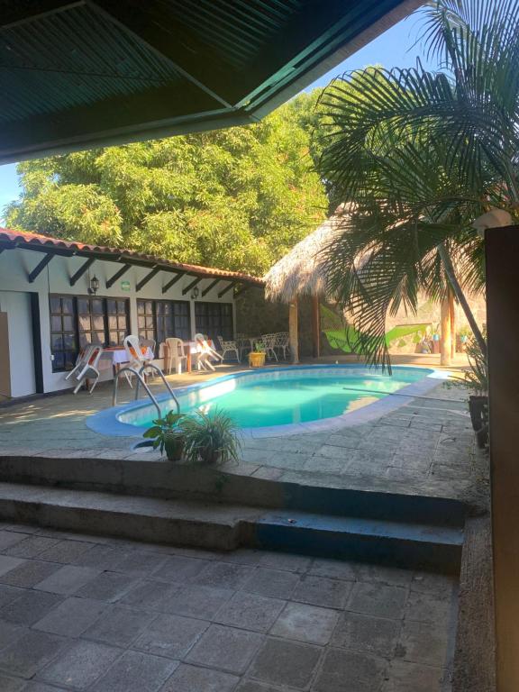 a swimming pool in front of a house at hotel Las Cabañitas 8873-3748 in Managua