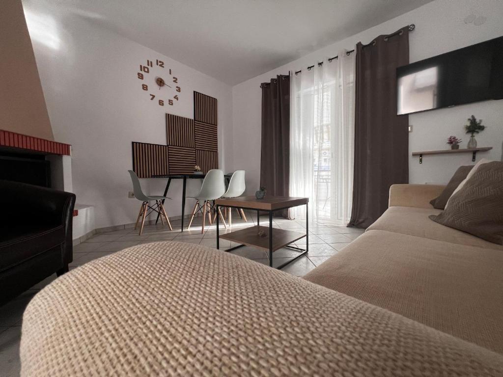 1 dormitorio con cama, mesa y reloj en Bella Maisonette, en Pefkohori