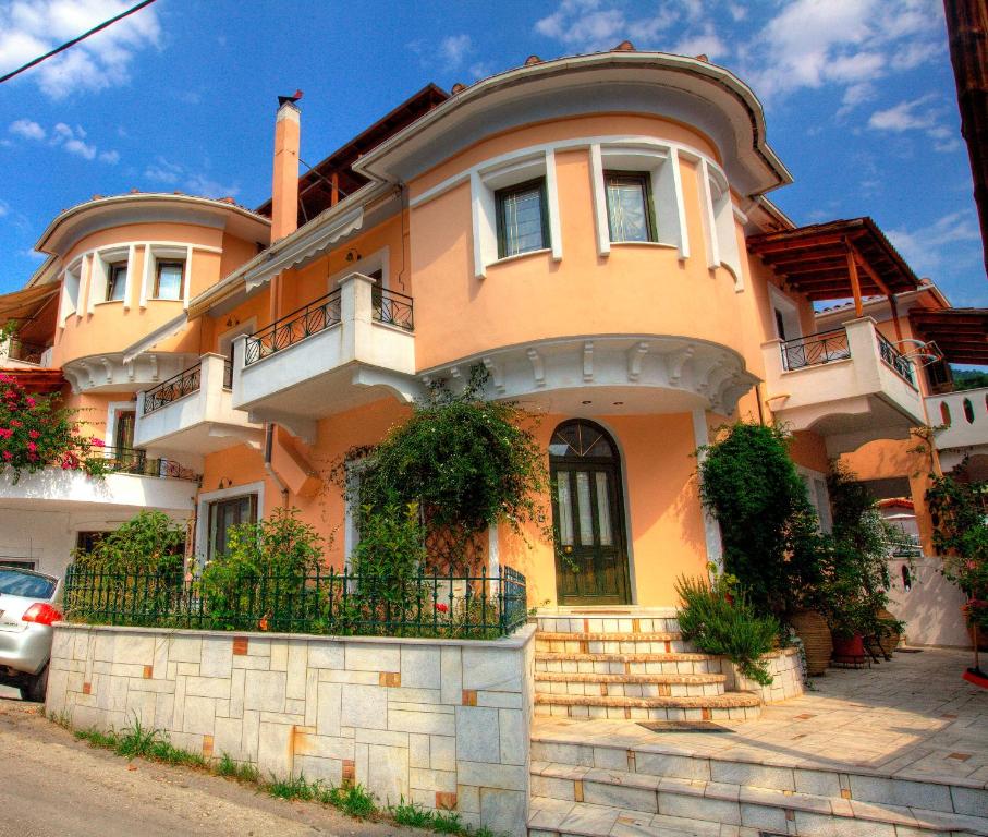 ein großes orangefarbenes Haus mit einer Treppe davor in der Unterkunft Ilian House in Parga
