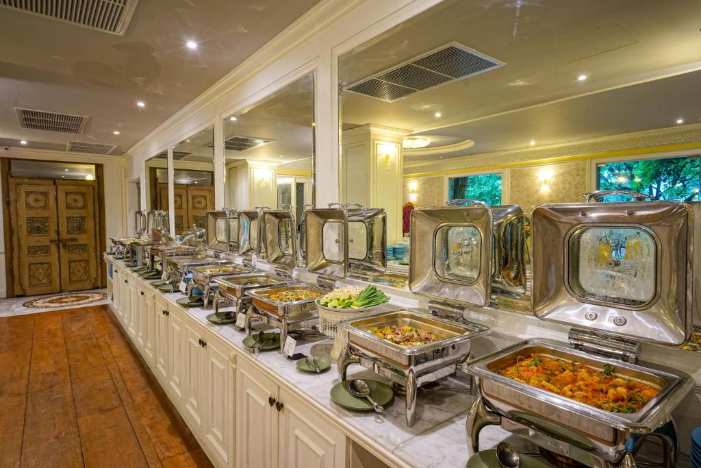 A long indoor buffet line presents hot dishes in stainless-steel serving trays.