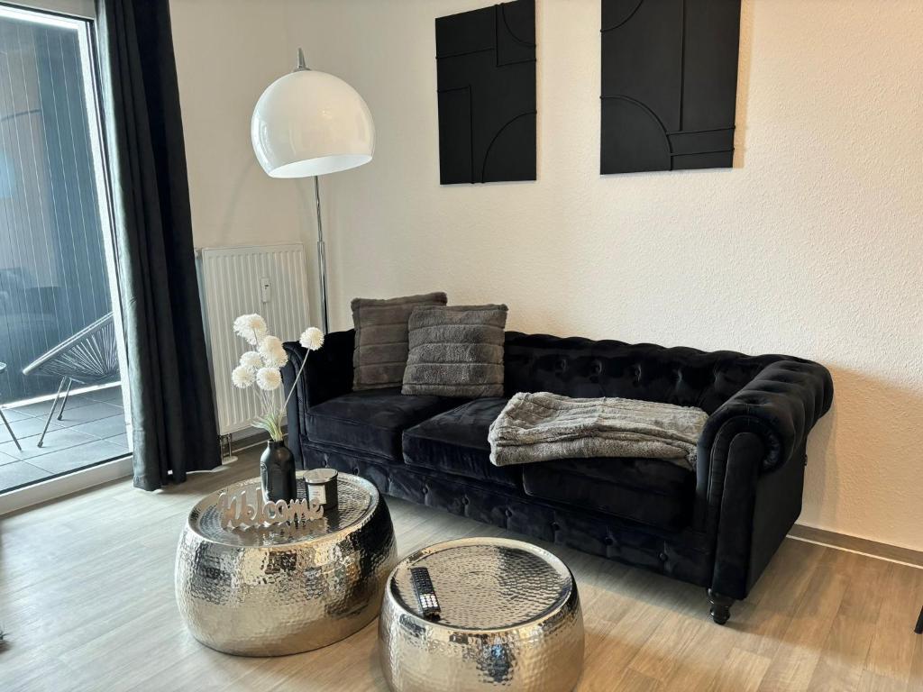 ein Wohnzimmer mit einem schwarzen Sofa und 2 Metalltischen in der Unterkunft Charming Homes - Studio 23 in Wolfsburg