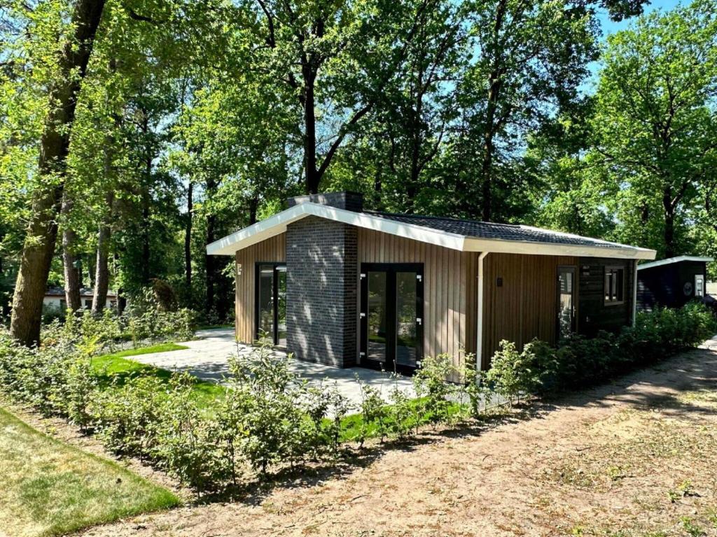 a small cabin in a park with trees at Chalet w Garden & Views in Hoenderloo