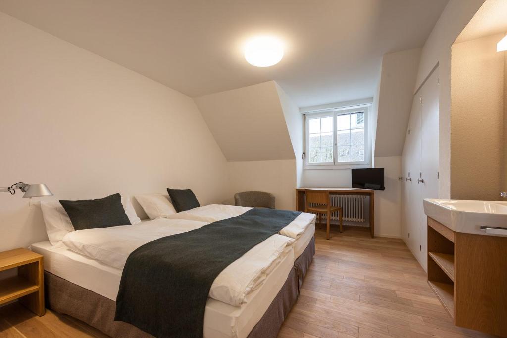 um quarto com uma cama grande e um lavatório em Gasthof Oxen em Küsnacht