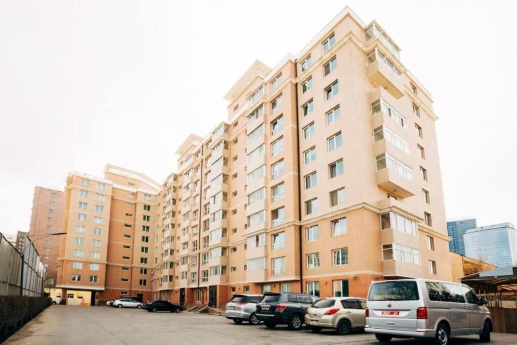 a large building with cars parked in a parking lot at Diplomat Apartment in Ulaanbaatar