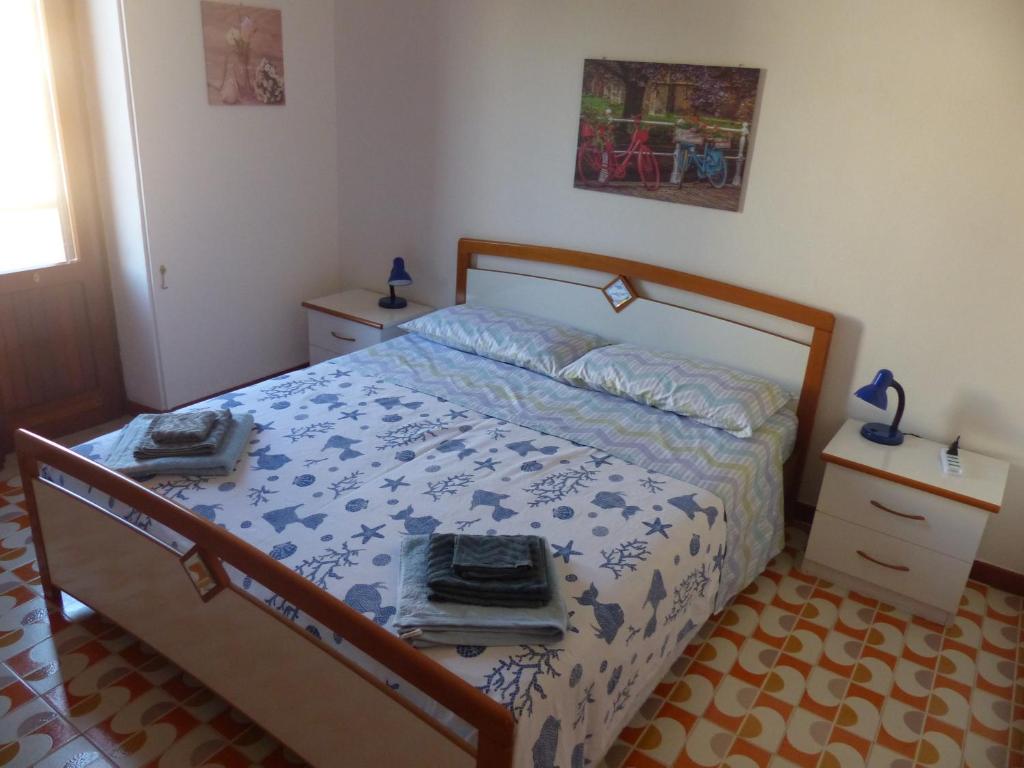 a bedroom with a bed with a blue and white comforter at Villetta Fiorita in San Vito lo Capo