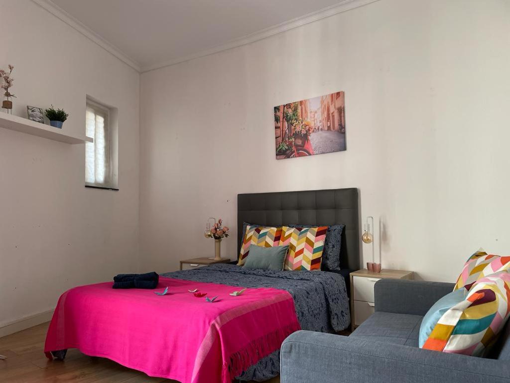 a bedroom with a bed and a couch with a pink blanket at By La Rambla Rooms in Barcelona
