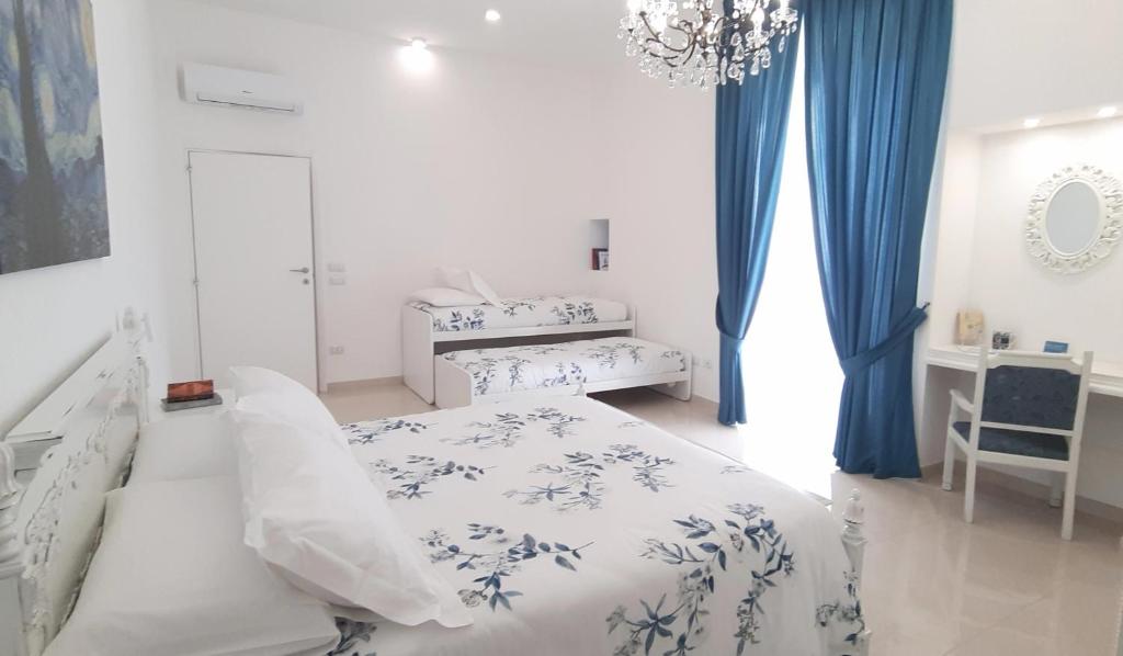 a white bedroom with a bed and a chandelier at Balcone in Valle d'Itria in Martina Franca