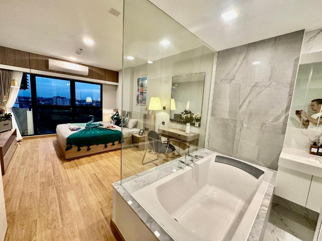 Un baño con bañera y un dormitorio con cama. en Astra Sky River Paronama Pool Luxury Changklan Chiang Mai, en Chiang Mai