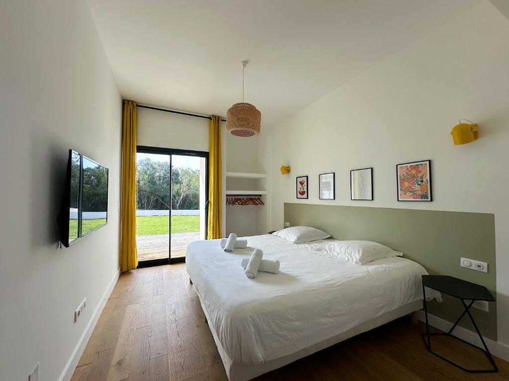a bedroom with a large white bed and a window at Villas de standing avec magnifique vue mer et piscines privées, Sagone in Sagone