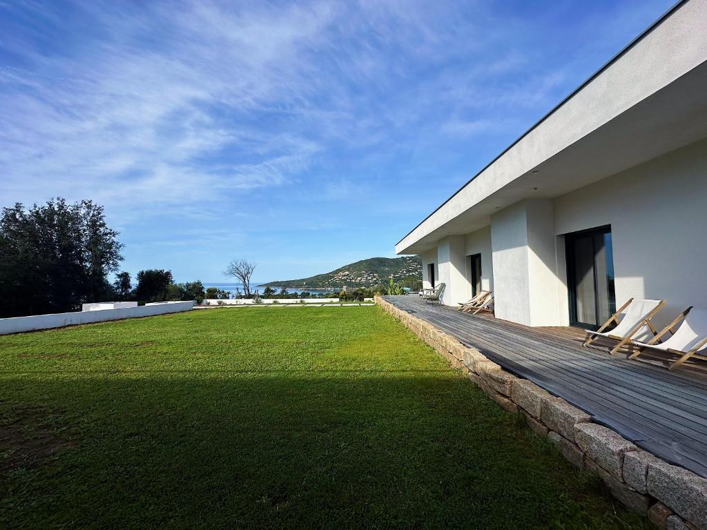 a house with two chairs sitting on a wooden deck at Villas de standing avec magnifique vue mer et piscines privées, Sagone in Sagone