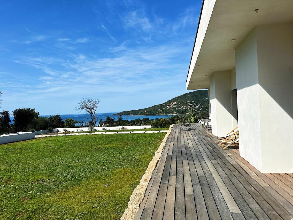 a wooden boardwalk leading to a house with a green field at Villas de standing avec magnifique vue mer et piscines privées, Sagone in Sagone