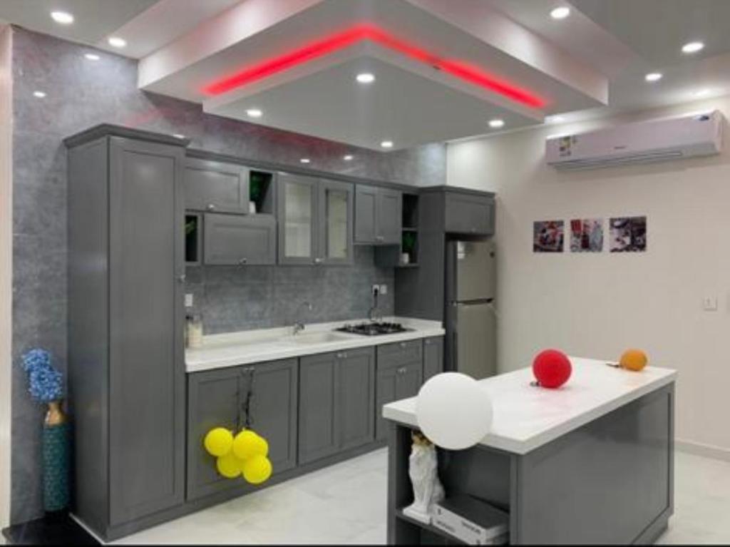 cocina con armarios grises y techo rojo en استراحة وشاليهات عزيزه, en Al Wajh
