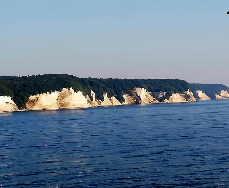 une grande étendue d'eau avec des falaises et des arbres dans l'établissement Wohnung am Wanderweg zum Königsstuhl unter Reet, à Lohme