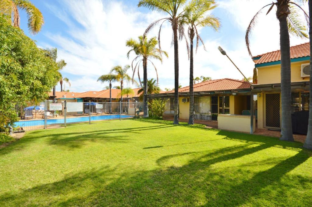 a large yard with palm trees and a house at Palm Garden Apartment - Kalbarri WA in Kalbarri