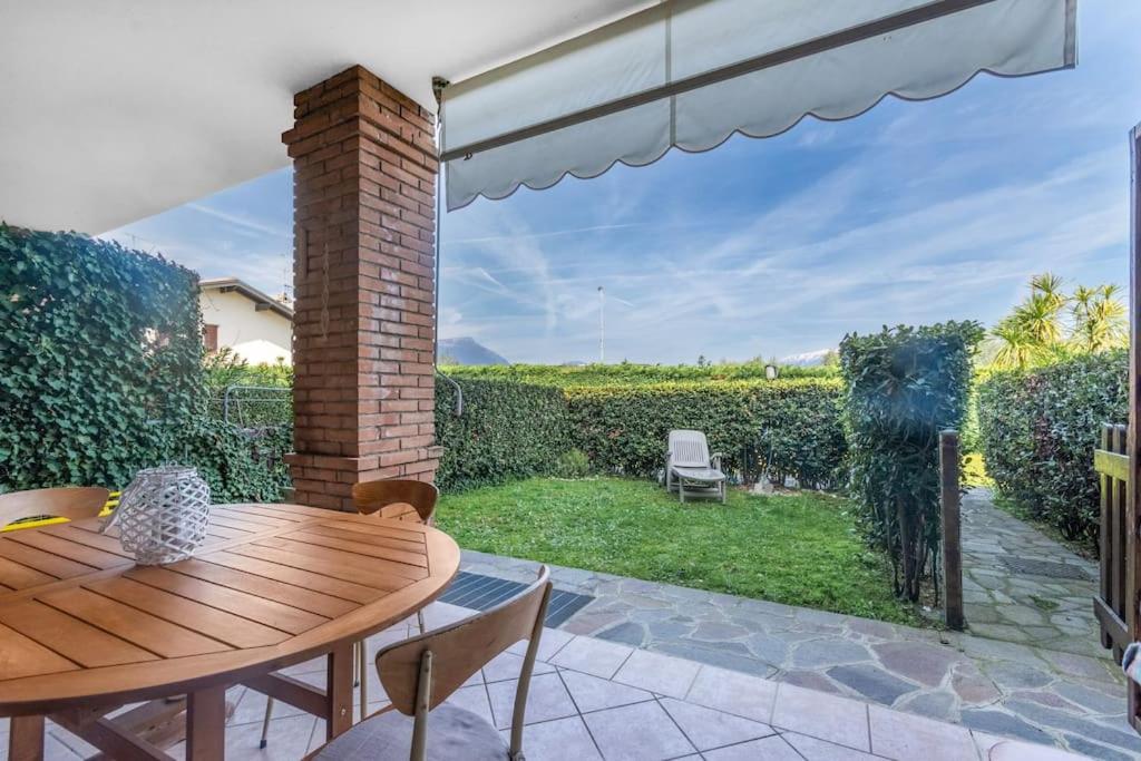 a patio with a wooden table and chairs and a window at Cherry House with Pool, Solarium Area and Barbecue in Manerba del Garda