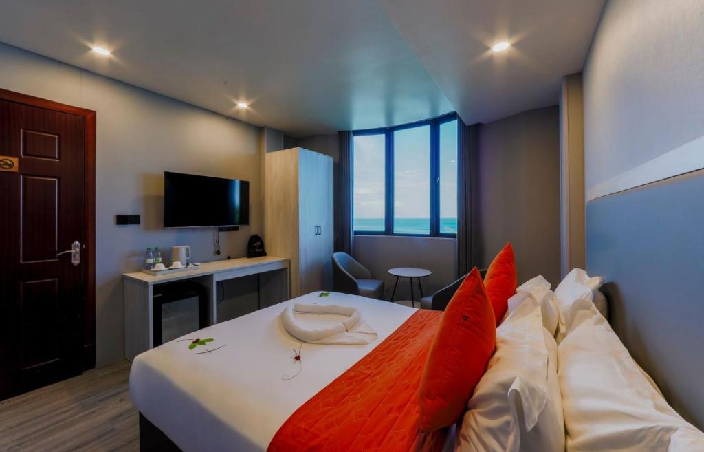 een hotelkamer met een groot bed met rode kussens bij Starry Beach Inn in Hulhumale