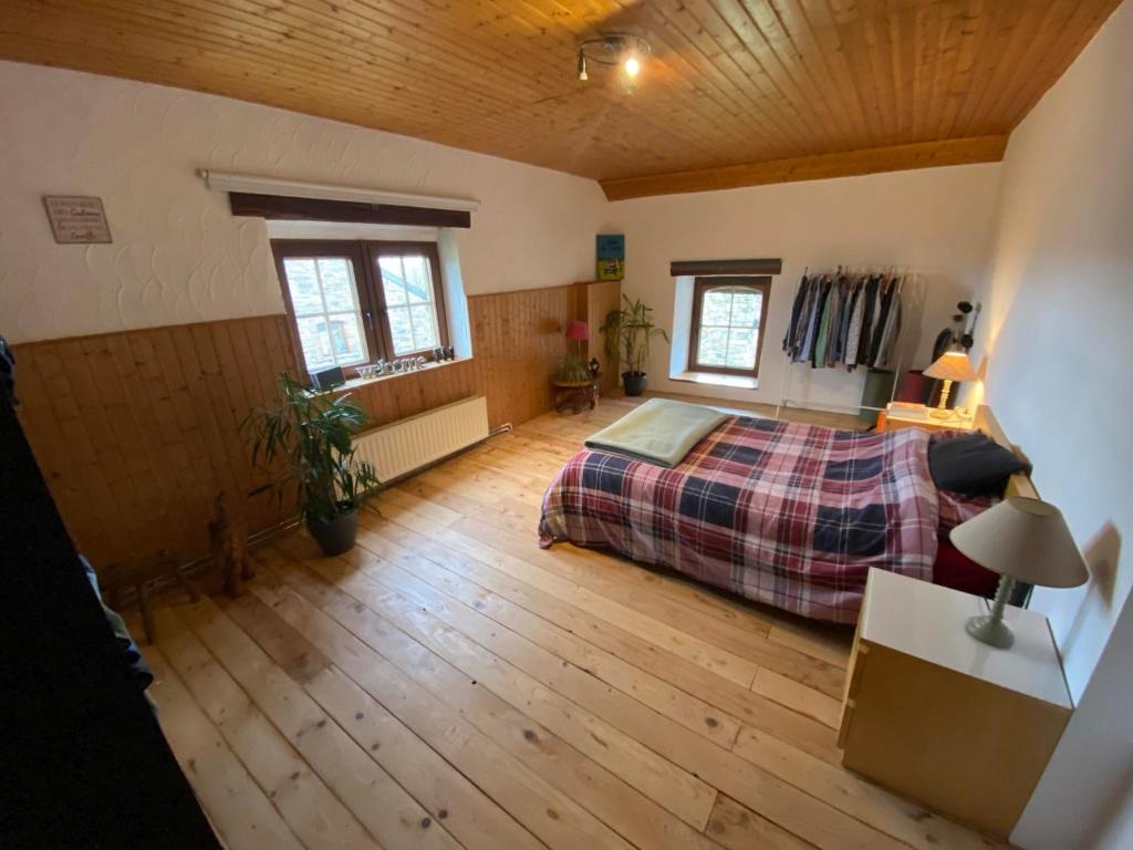een slaapkamer met een bed en een houten vloer bij F1 Room 2 - Cour-toise in Stoumont