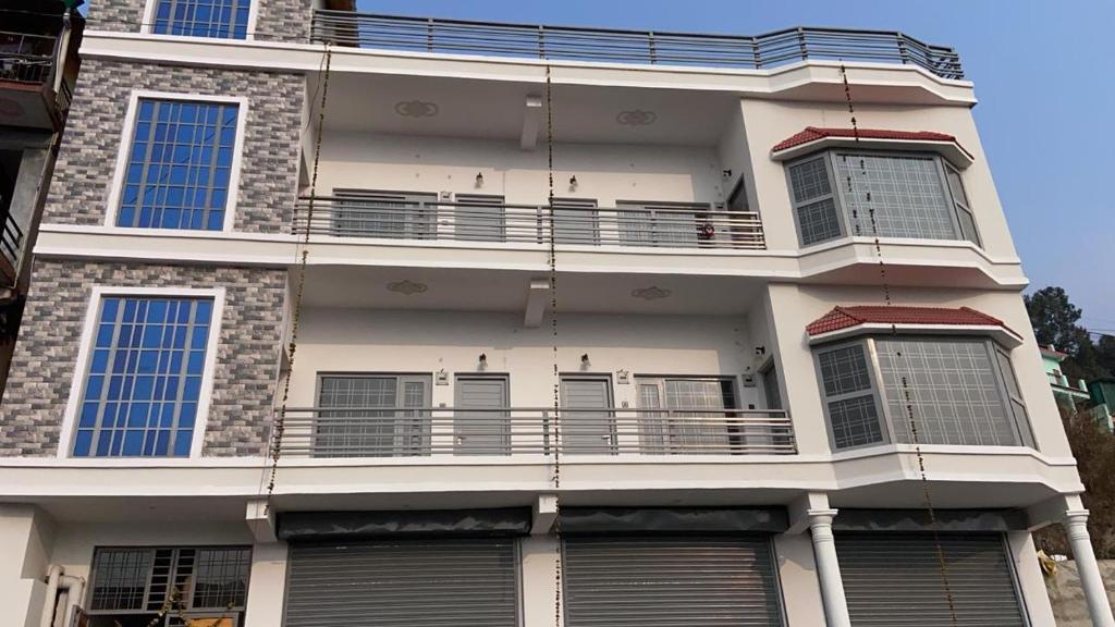 ein hohes weißes Gebäude mit Balkon darüber in der Unterkunft The Hill Paradise in Bhowāli