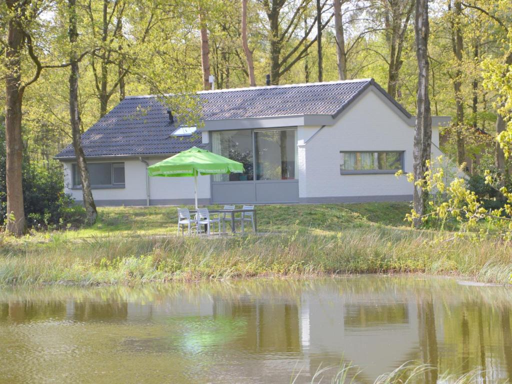 a house with a green umbrella next to a body of water at Alluring Holiday Home in Limburg near Forest in De Horst