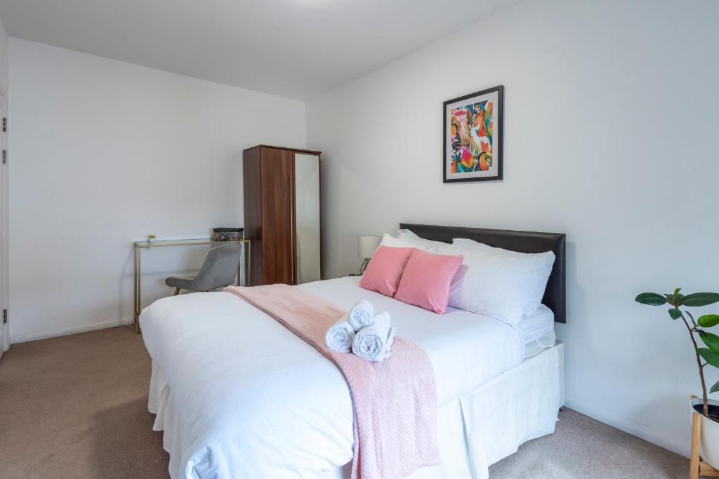 a bedroom with a white bed with pink and white pillows at Dazzling Room near Paddington/Elizabeth Stn in London