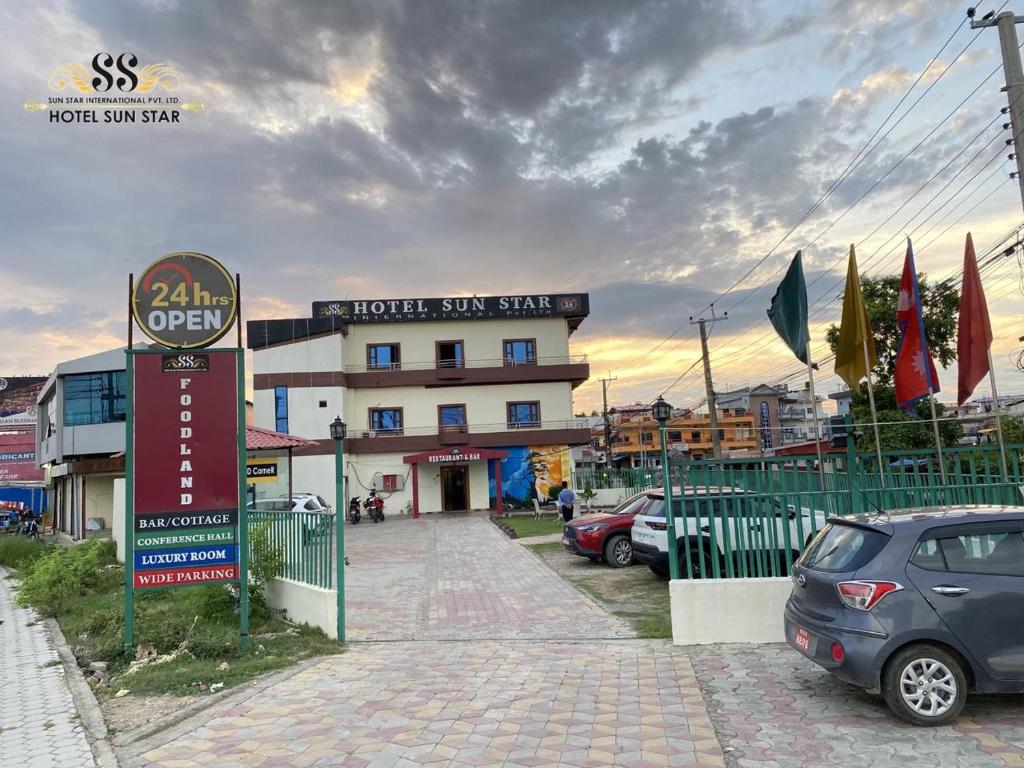 a hotel sign with cars parked in front of a building at Sun Star International Hotel 24/7 in Bhairāhawā