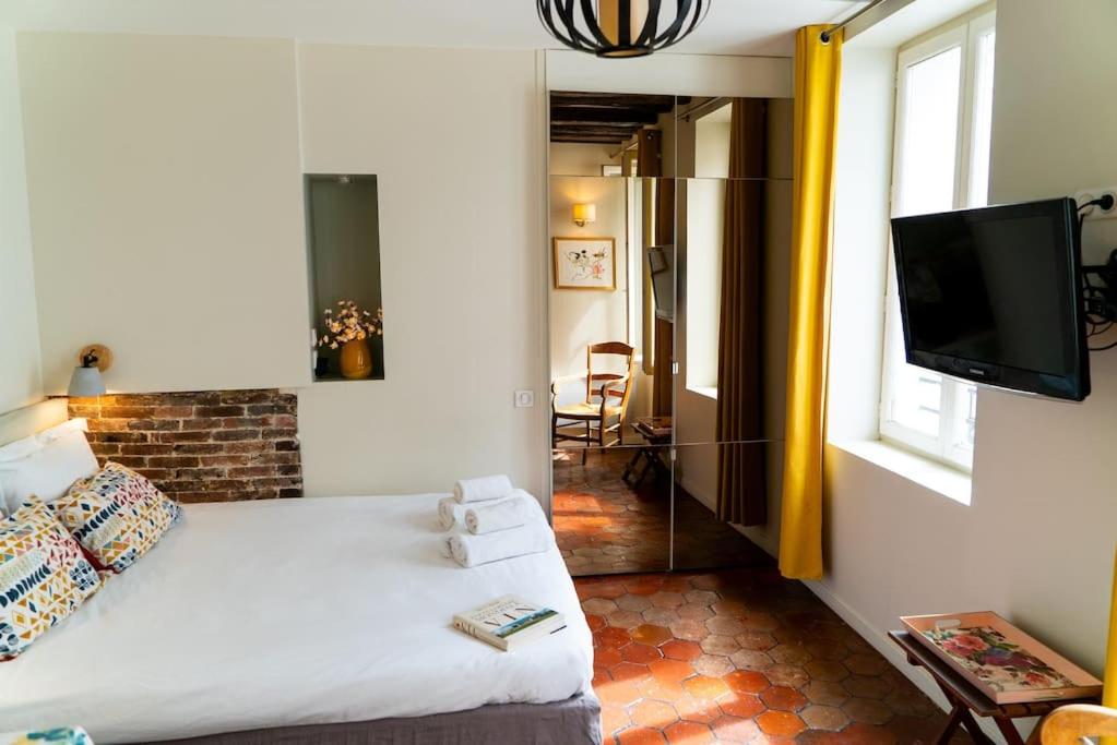 une chambre avec un lit, une télévision et une fenêtre dans l'établissement Studio cosy au cœur de Paris, à Paris