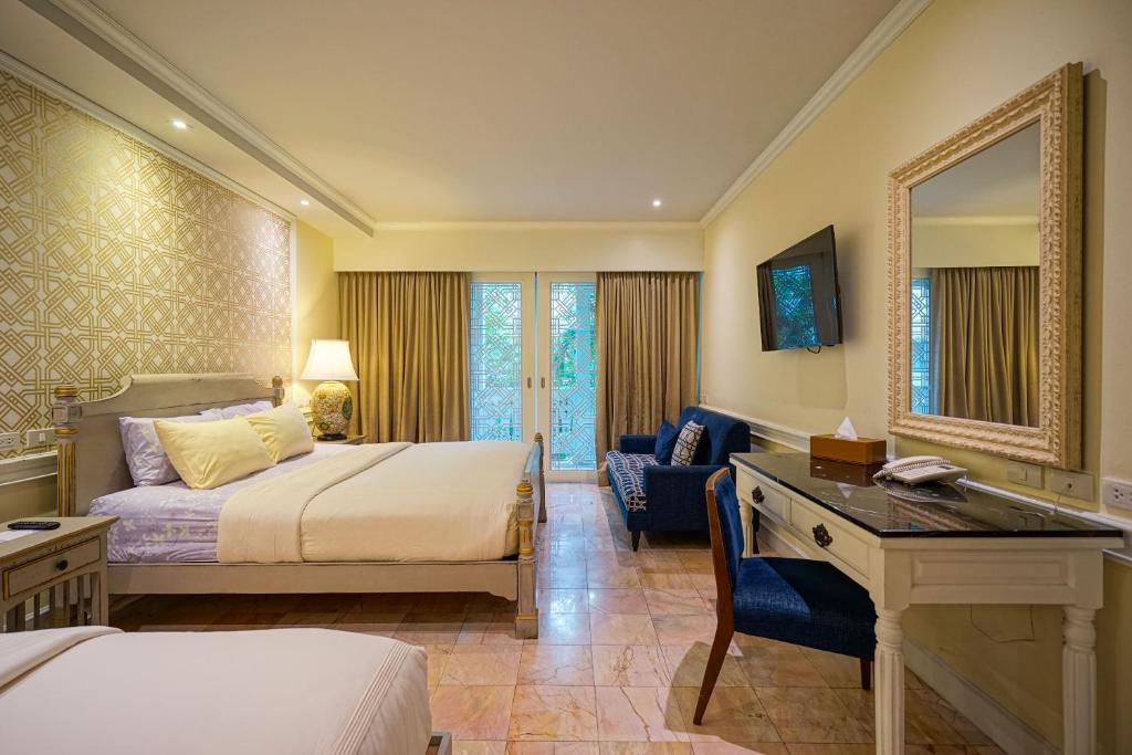 A large bedroom with a bed, separate writing desk, lounge chair and balcony doors.