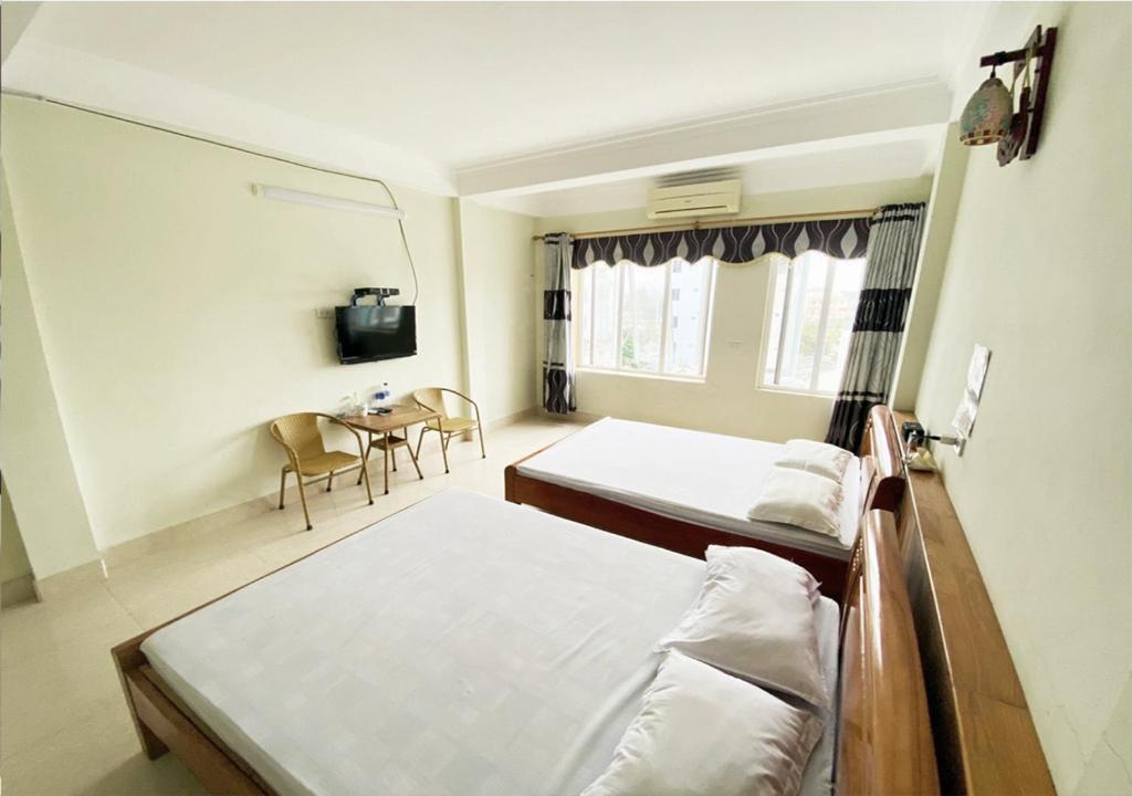 um quarto com duas camas e uma mesa em Coto Plus Hotel & Restaurant em Quang Ninh