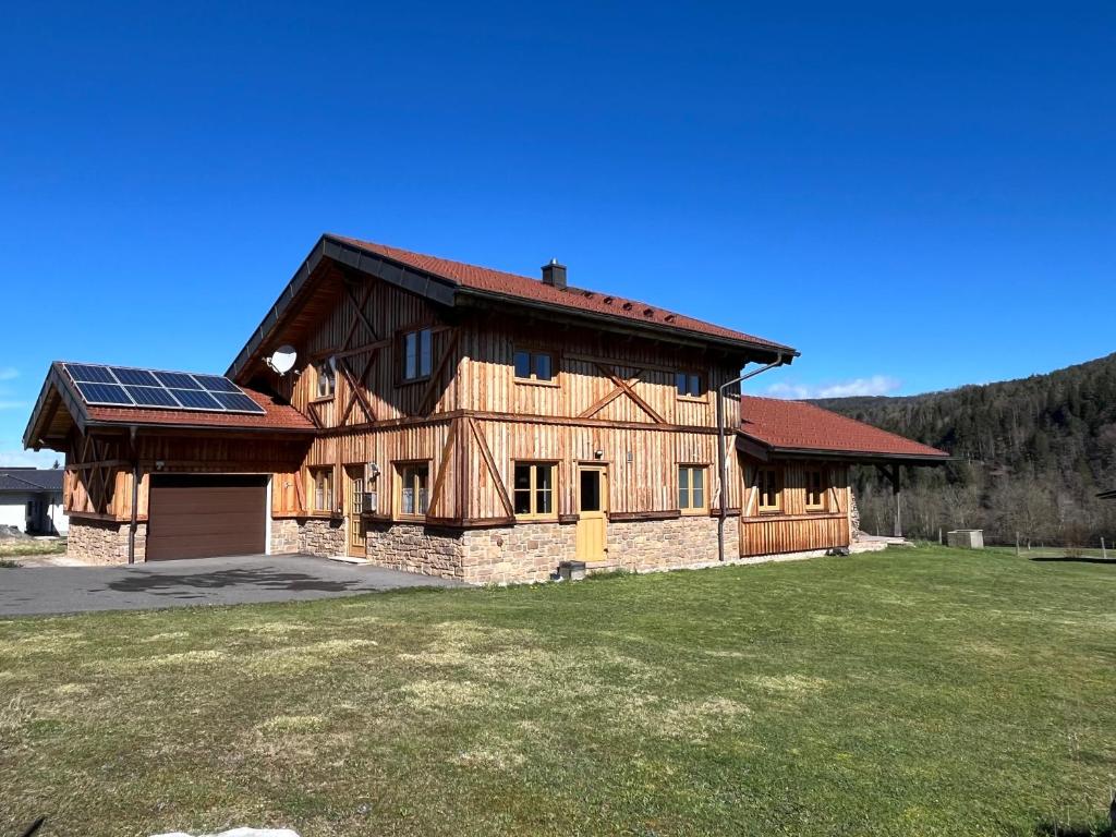 a large wooden house with a solar roof at Ferienhaus an der Drau in Sankt Oswald