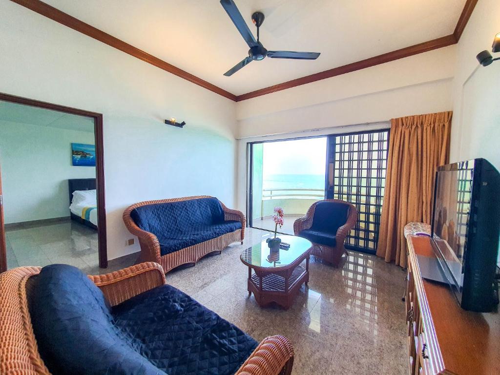 uma sala de estar com sofás azuis e uma televisão em 'Sunny seaview condo' at Regency by Shine Stay em Porto Dickson