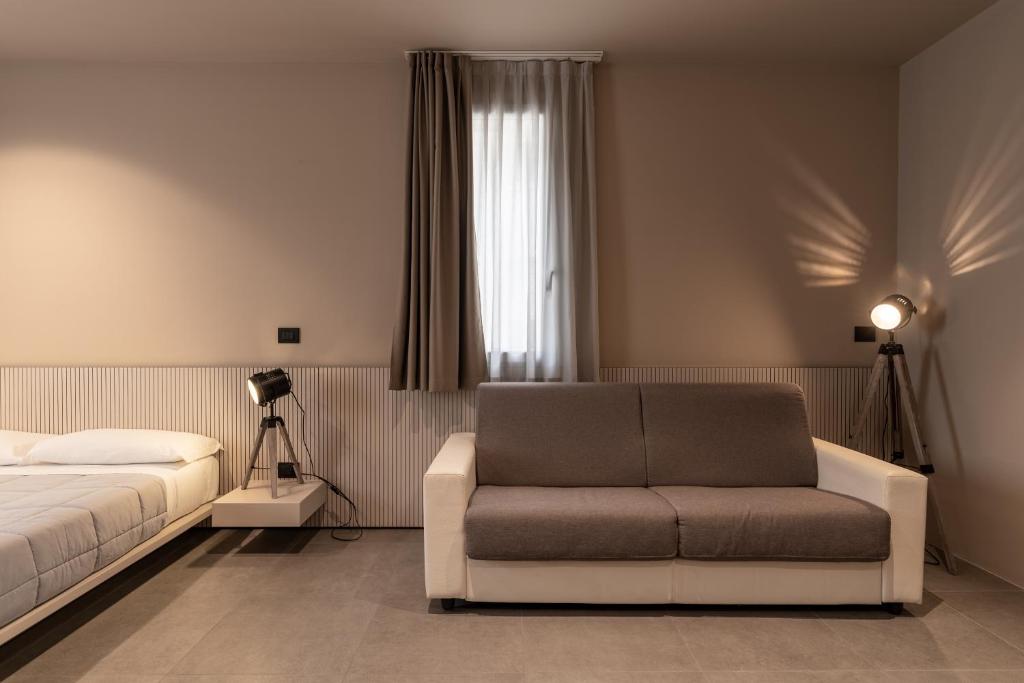 a bedroom with a bed and a couch and a window at Amare Suite & Apartments in Bellaria-Igea Marina