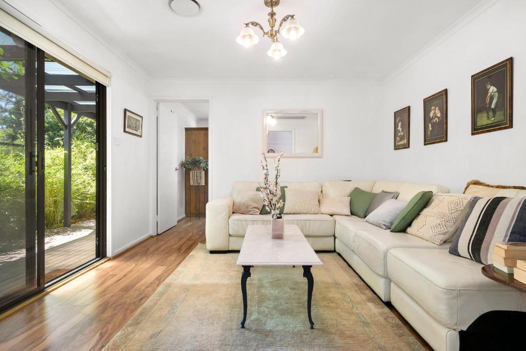 un soggiorno con divano e tavolo di Tranquil 3-Bedroom Retreat in Narrabundah a Narrabundah