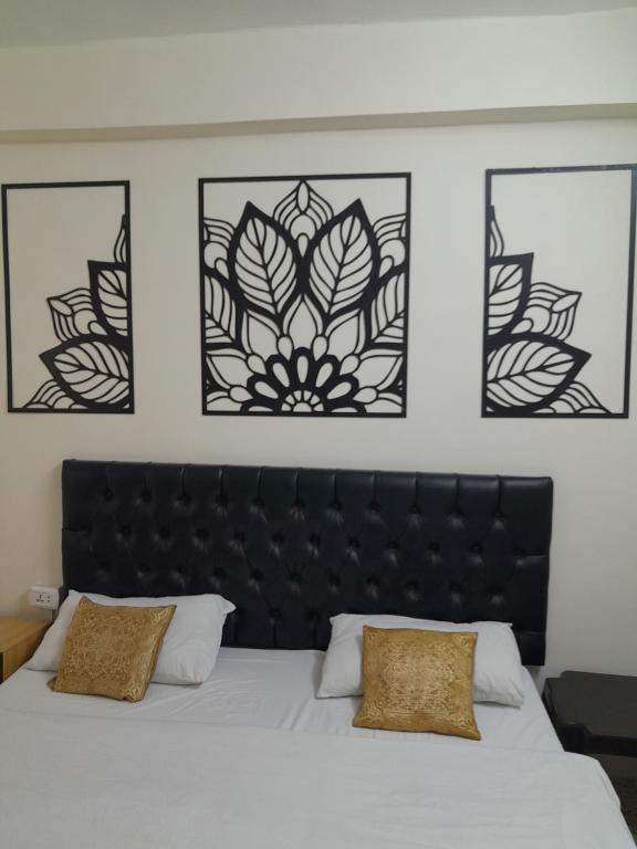 um quarto com uma cabeceira preta e três quadros emoldurados em Hamoudah Hotel em Amã